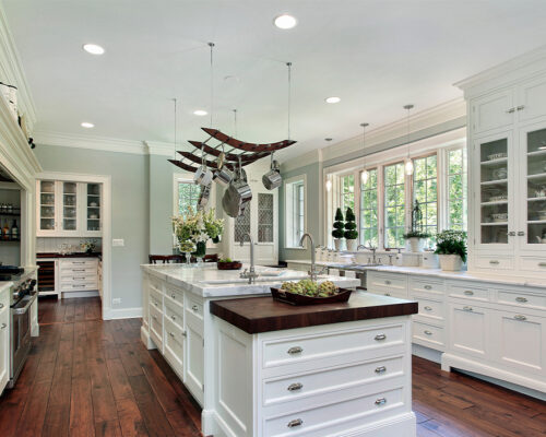 Newly remodeled kitchen with white cabinets, wood floors, and large windows.
