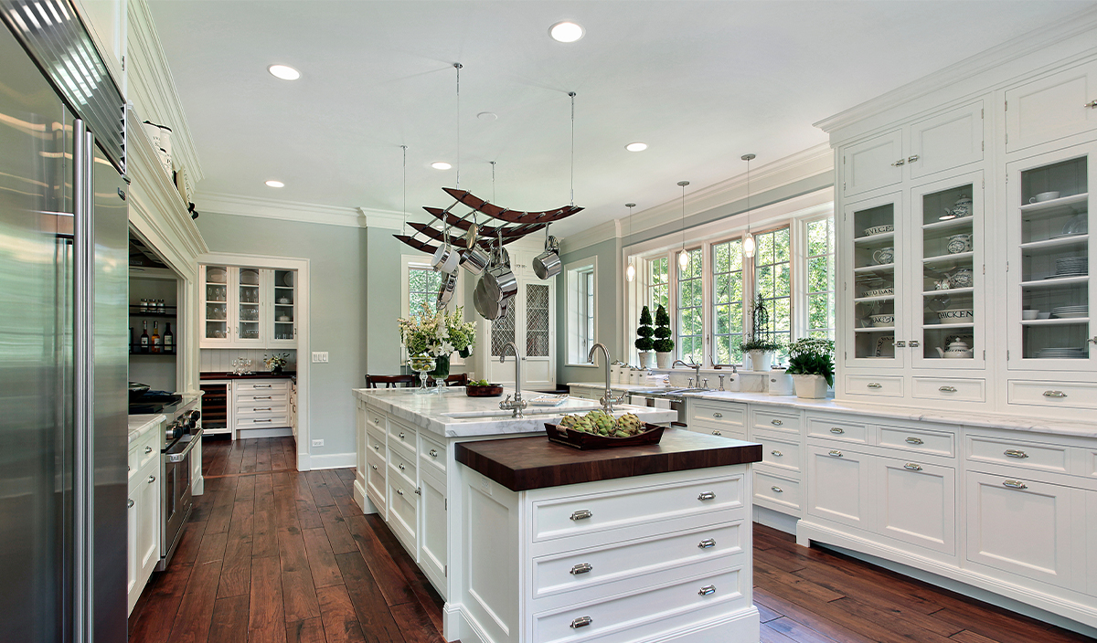 Newly remodeled kitchen with white cabinets, wood floors, and large windows.