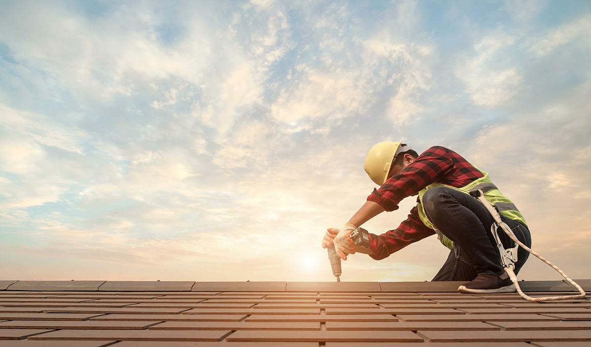 Construction worker repairing the roof of a residential home.